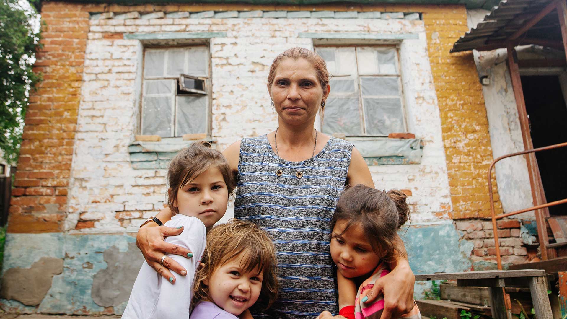 A woman and three children outside their home, Ukraine.