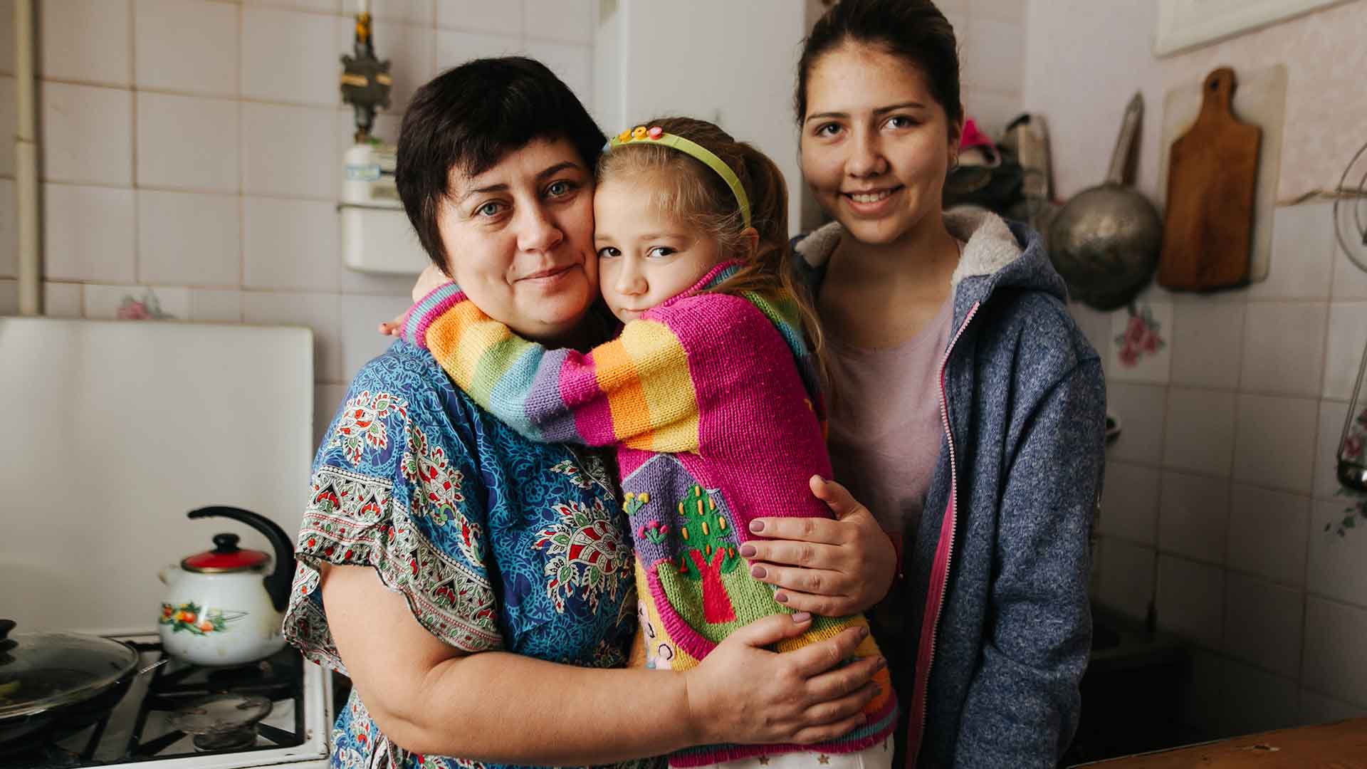 A family stood in their small kitchen.